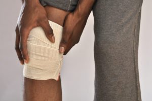 A man holds his bandaged knee.