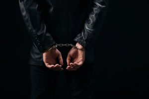 A man with his hands handcuffed behind his back.