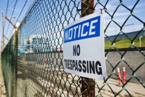 A no trespassing sign on a chain link fence.