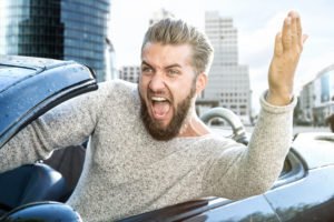 An angry man gesturing out of his car window.