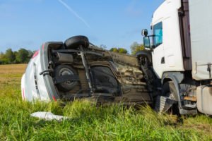 A car on its side after a T-bone crash with a truck.