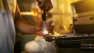 A man fills a small bag with drugs.