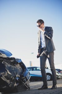 A man looks shocked looking at car damage.