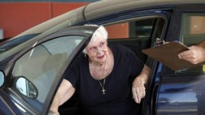 An older driver hands a police officer her license.