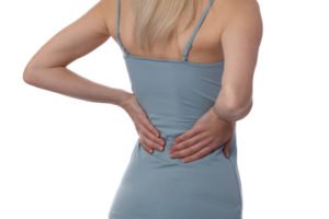 A woman grabbing her back in pain.