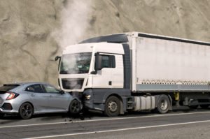 A frontal collision between a white truck and a silver car.