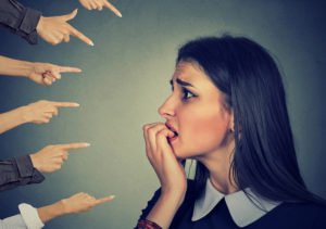 nervous woman with a bunch of hands pointing at her