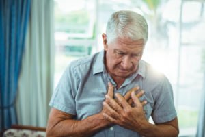 An older man holding his chest in pain.