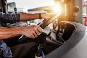 close-up of commercial truck driver’s hands on steering wheel