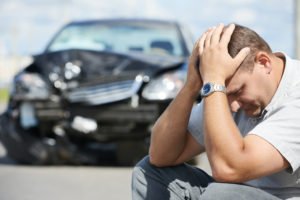 upset driver in front of damaged car