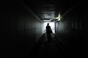 woman walks through a poorly lit tunnel