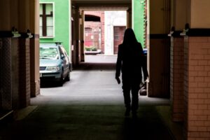 woman walking through dark tunnel to parking lot