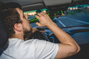 man drinks behind the wheel