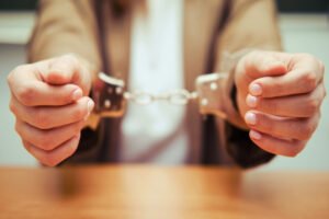 man in handcuffs behind table