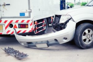 Car with a damaged front bumper after a collision with a truck